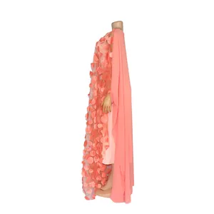 Side view detail of a coral African maxi dress featuring 3D floral applique and chiffon cape