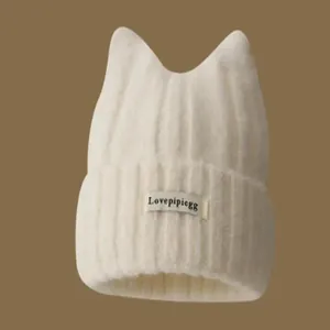 Close-up of a white knitted winter beanie with cute cat ears and a small logo tag