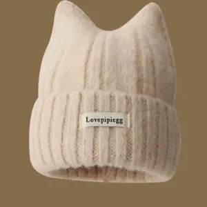 Detailed view of beige ribbed knit winter beanie featuring cute cat ears and a front label