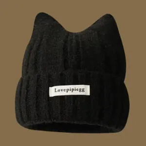Close-up view of a black knitted cat ear beanie with a white Lovepipiegg brand label