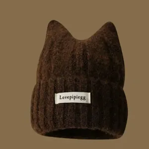 Close-up view of a dark brown knit beanie featuring cute cat ears and a logo label