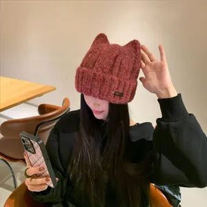 Chic burgundy cat ear knit beanie hat for women worn by a model in winter cozy style