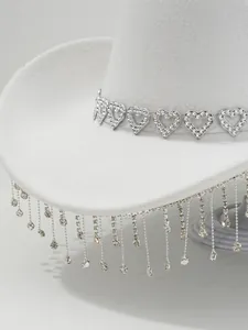 Close-up of a white cowboy hat with rhinestone heart band and dangling crystal tassels.
