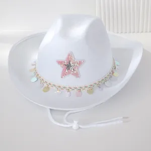 Detailansicht eines weißen Cowboyhuts mit rosa Paillettenstern und schillernden Fransen