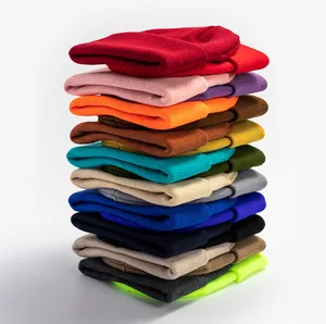 Pile de bonnets en maille de diverses couleurs unies montrant texture et variété