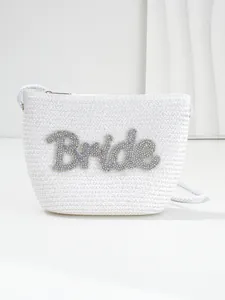 Detail view of the shimmering rhinestone Bride lettering on a white woven straw bag