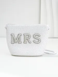 Detailed view of white woven bridal straw bag with pearl and rhinestone MRS lettering