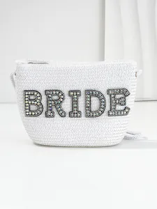 Detailed shot of white straw bride bag featuring sparkling rhinestone lettering.
