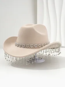 Detailed shot of beige cowboy hat featuring heart rhinestone trim and sparkling tassels.