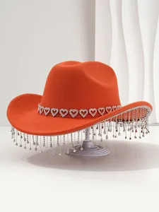 Close-up of orange cowboy hat featuring heart rhinestone band and crystal fringe tassels