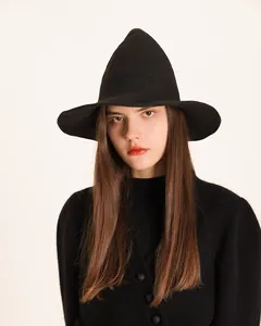 Detailed front view of a black knitted pointed witch hat worn by a model for Halloween