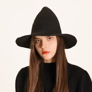 Detailed view of a black knitted pointed witch hat worn by a model for Halloween party.