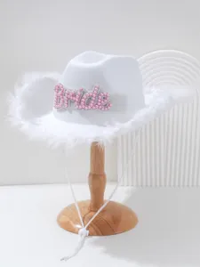 Detailed view of white bride cowboy hat with pink pearl letters and feather trim