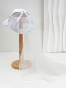 Dettaglio di un cappellino da sposa bianco a rete con lungo velo in tulle su piedistallo.
