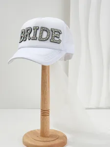 Vista dettagliata del cappello da sposa bianco con lettere in strass e lungo velo.