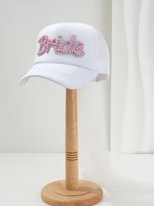 Dettaglio del cappellino bianco da sposa con perle rosa e lungo velo bianco fluente