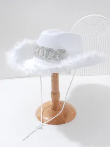 Detailed view of white bride cowboy hat with rhinestone BRIDE letters and feather trim