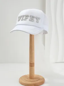 Dettaglio di un cappello da sposa bianco con scritte WIFEY in perle e velo fluente elegante