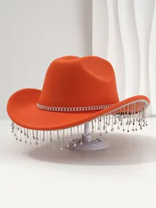 Detailweergave van een oranje vilten cowboyhoed met fonkelende franjes van strass-steentjes