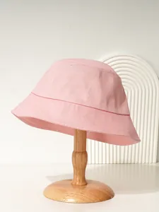 Detailansicht eines stylischen rosa Anglerhuts aus Baumwolle auf einem Holzständer
