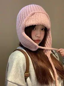 Vista dettagliata di un cappello di maglia rosa con paraorecchie e lacci per l'inverno