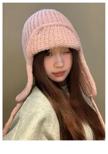 Cappello da trapper in maglia rosa con paraorecchie indossato da una modella in interno