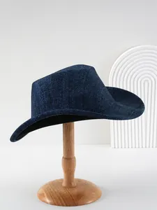 Detailopname van een donkerblauwe westernhoed met brede rand op een houten houder
