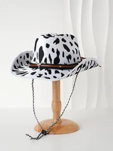 Close-up of a cow print cowboy hat with bull head buckle displayed on a wooden stand.