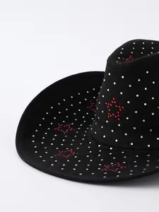 Primo piano di un cappello da cowboy in pelle scamosciata nera con strass e stelle rosse.