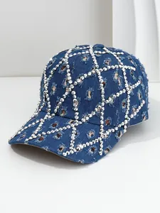 Detalle de gorra de béisbol de mezclilla desgastada con patrón de rejilla de pedrería plateada.