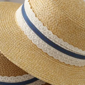 Close-up detail of a French raffia straw hat featuring white lace and blue ribbon trim.