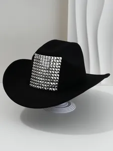 Close-up detail of a black cowboy hat featuring a square patch of silver pyramid studs