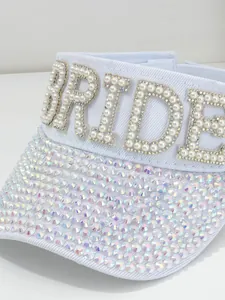 Dettaglio di un cappello a visiera bianca con lettere BRIDE di perle e strass luccicanti