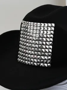Close-up macro detail of silver pyramid studs on a classic black felt Western cowboy hat