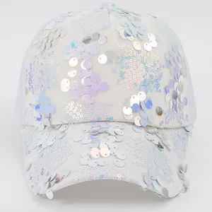 Detailed view of shimmering sequins and embroidery on a Y2K style white baseball cap.