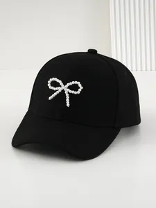 Primo piano di un cappellino da baseball nero con fiocco di perle bianche eleganti.