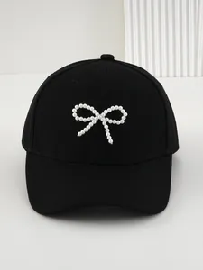 Vista dettagliata di un berretto da baseball nero con un elegante fiocco di perle bianche.