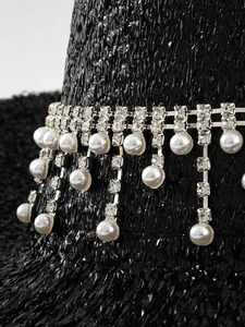 Detail view of luxury black party hat with sparkling rhinestones and pearl pendants.