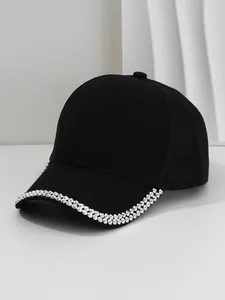 Close-up detail of silver metallic studs on the curved brim of a black vintage baseball cap
