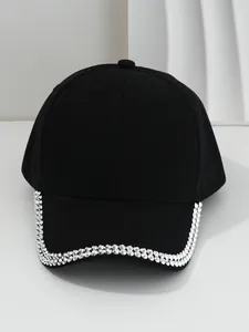 Detail view of a black baseball cap featuring decorative silver metallic studs on the brim.