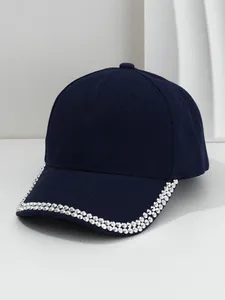 Detailed close-up view of navy blue baseball cap with silver metal studs on the brim