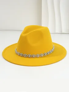 Close-up detail of a bright yellow fedora hat featuring a bohemian jeweled band