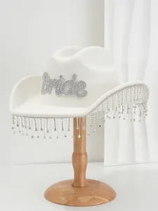 Detail of white bridal wool felt hat with rhinestone Bride logo and crystal tassels.