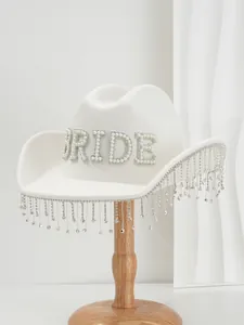 Close-up detail of white wool cowboy hat with pearl BRIDE lettering and rhinestone fringe.