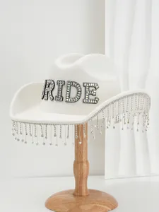 Detailed view of white bride cowboy hat featuring rhinestone letters and tassel fringe