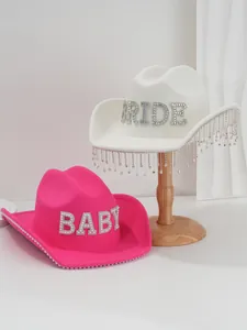 Detailed view of white and pink cowboy hats with rhinestone letters and pearl tassels