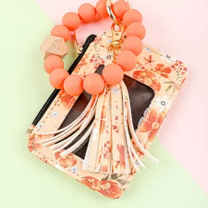 Detailed macro shot of floral print leather card holder with coral silicone bead wristlet