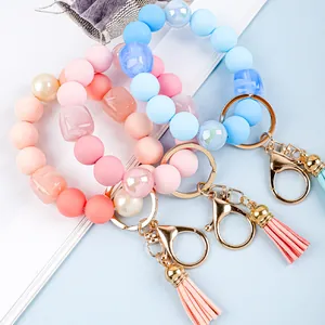 Detailed macro view of colorful silicone bead wristlet keychains with leather tassels.