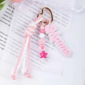 Close-up detail of a pink hand-woven rope keychain featuring a Mama charm and star beads