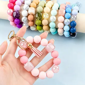 Hand holding a pastel pink silicone bead wristlet keychain with a soft tassel detail.